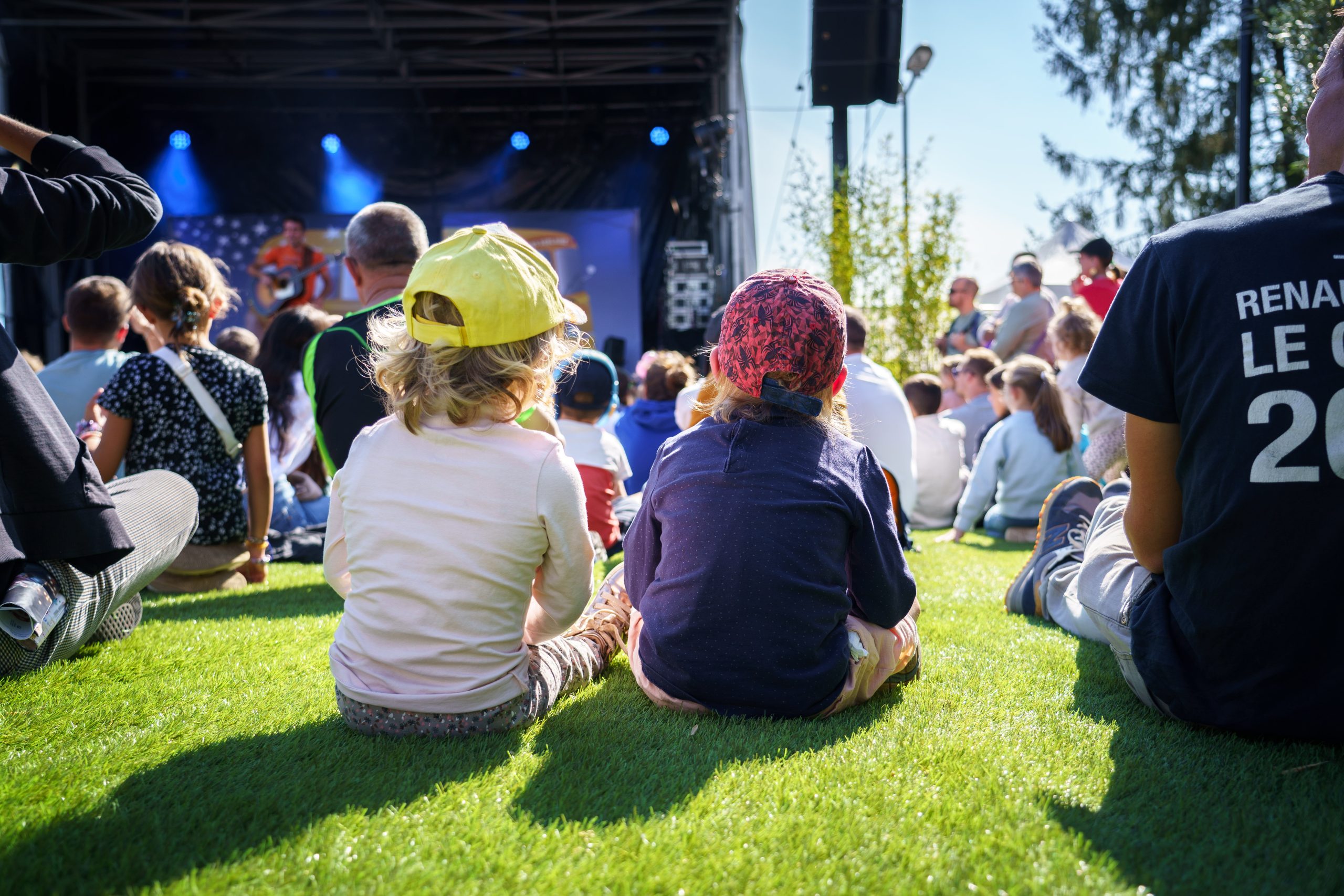 Enfants de dos regardant un concert organisé par la foire